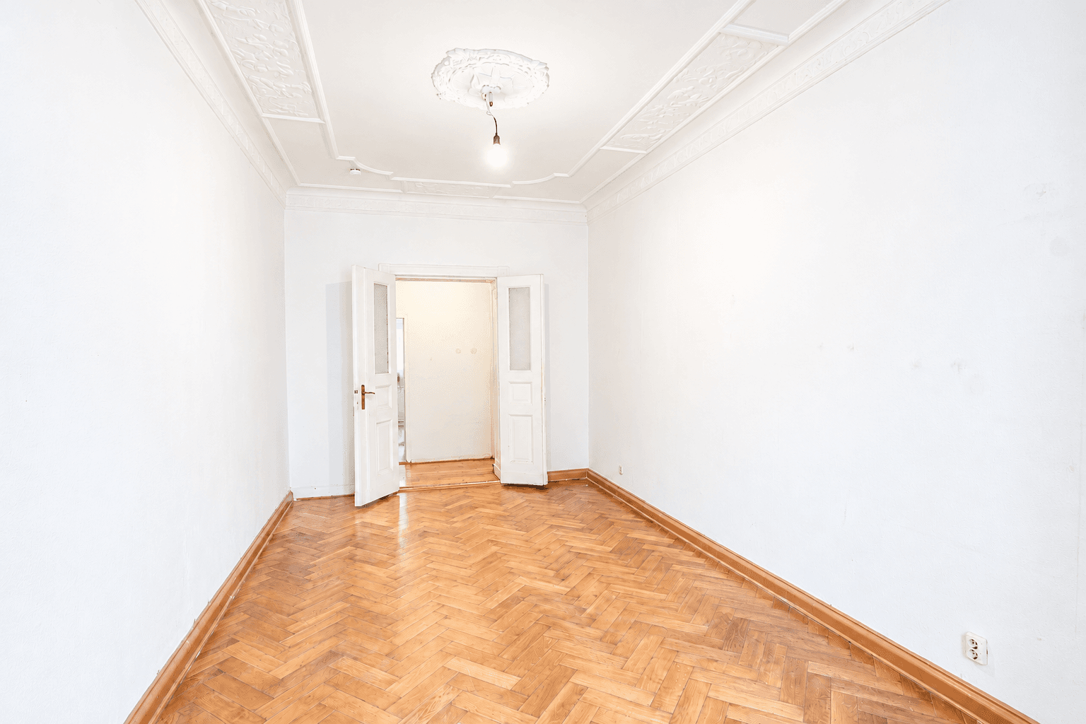 Wohnraum mit Fischgrätparkett und Stuck in der Hufelandstraße 18